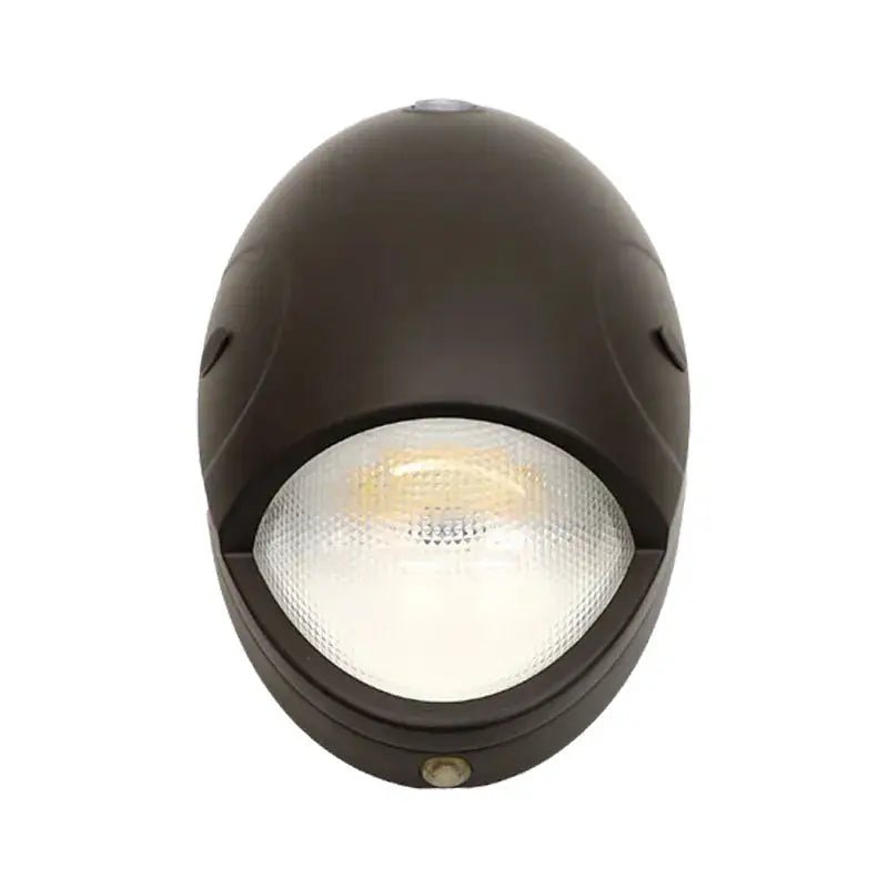 Oval bronze wall pack with photocell, 15W exterior lighting fixture by Westgate, showing the illuminated fixture on a wall.